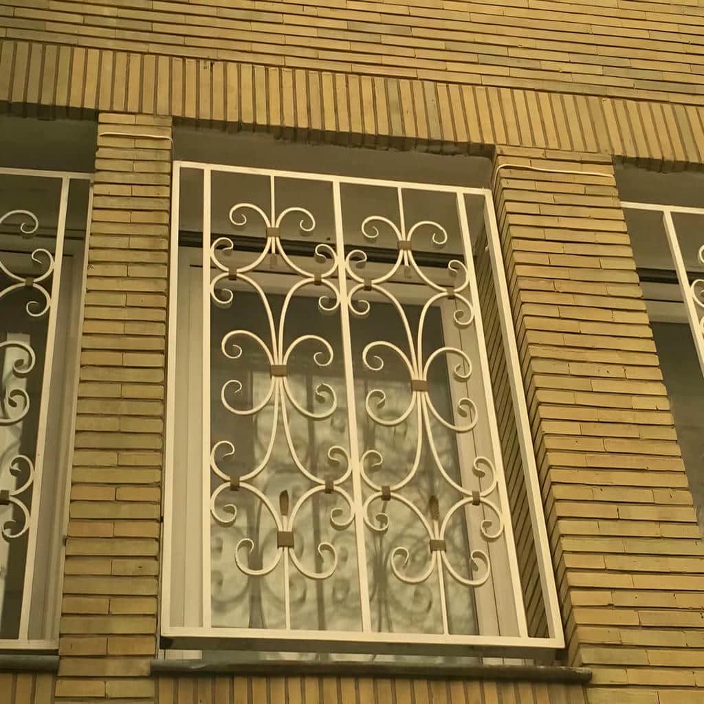 نرده پنجره سفید روی نمای آجری ساختمان
